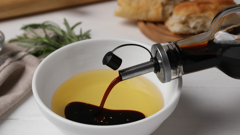 Balsamic vinegar being poured into a ramekin with olive oil