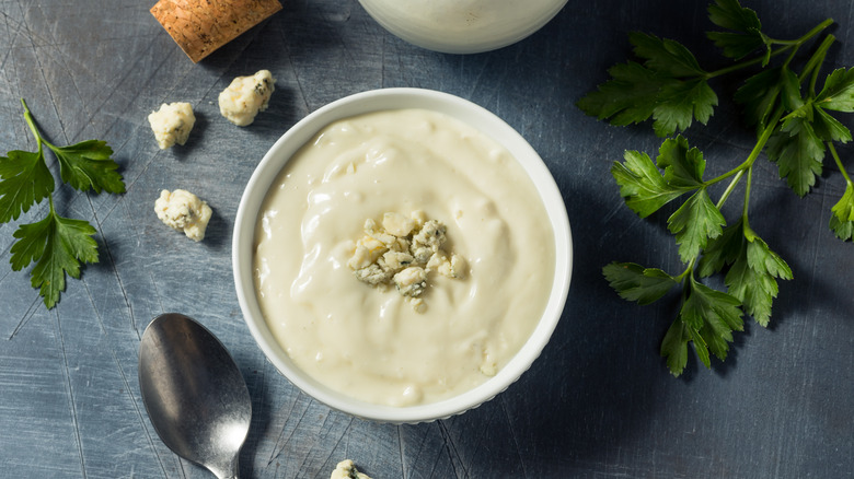 Homemade blue cheese dressing in white bowl with herbs