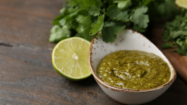 Lime and cilantro dressing with half a lime and a bunch of coriander in the background