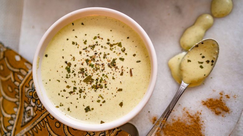 Tahini salad dressing in white bowl, with spoon alongside