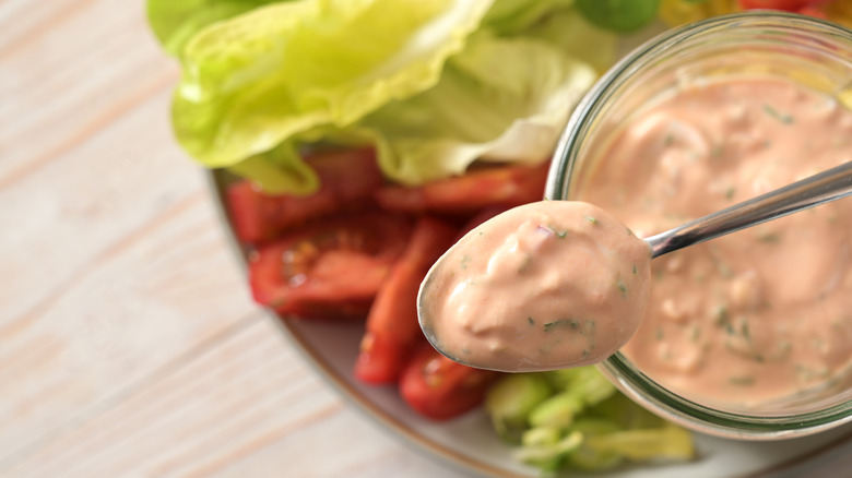 Thousand Island sauce on a spoon, with lettuce and tomato in the background