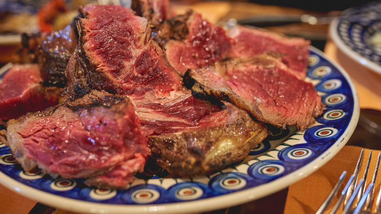 Thickly sliced bistecca alla Fiorentina on a vibrant blue plate