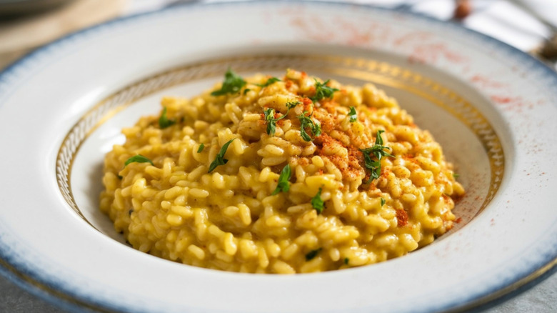 A plate of creamy risotto alla Milanese topped with fresh herbs