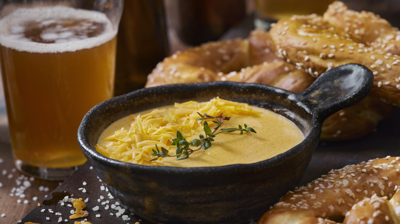 A bowl of beer cheese with pretzels and beer