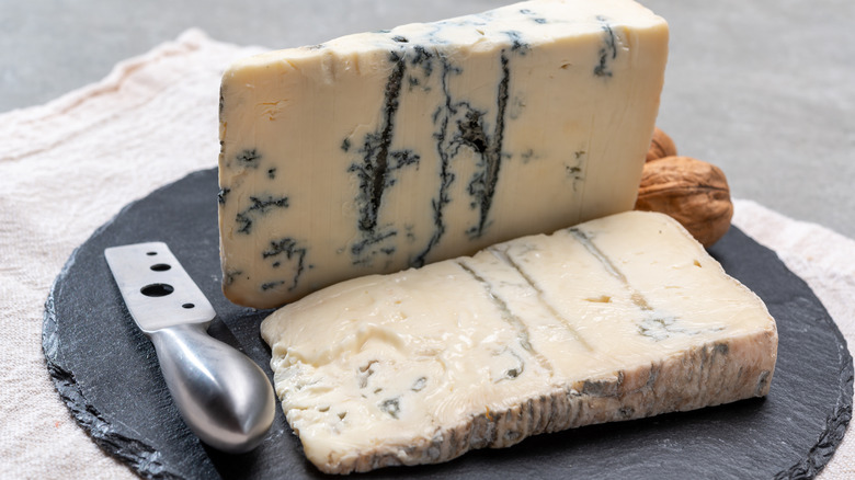 A block of gorgonzola dolce cheese with a knife and a slice cut off