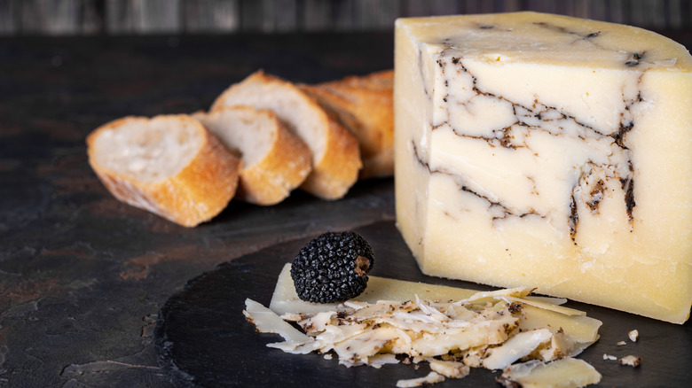A block of truffle pecorino cheese with slices of cheese, a truffle, and bread
