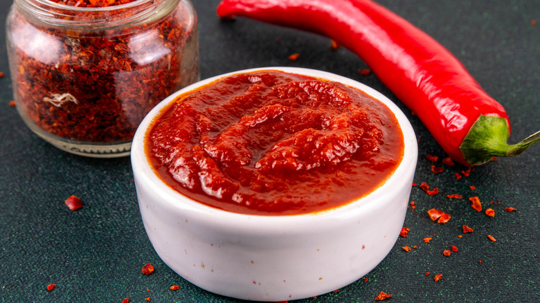 Dish of gochujang besides jar of red pepper flakes