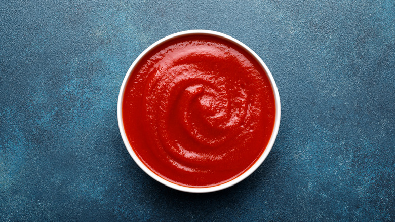 Ketchup in a bowl on blue background