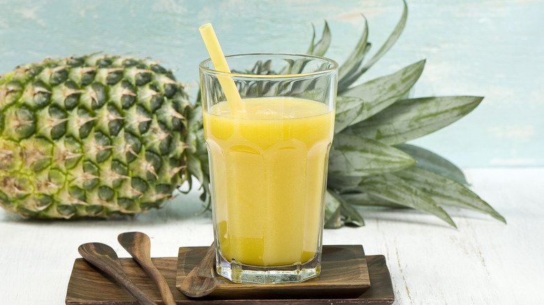 Glass of juice in front of whole pineapple fruit