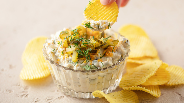 Person dipping chips into bowl of pickle cream cheese