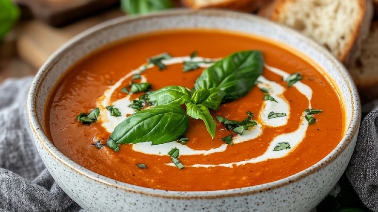 Bowl of tomato soup with swirl of alfredo sauce and fresh basil