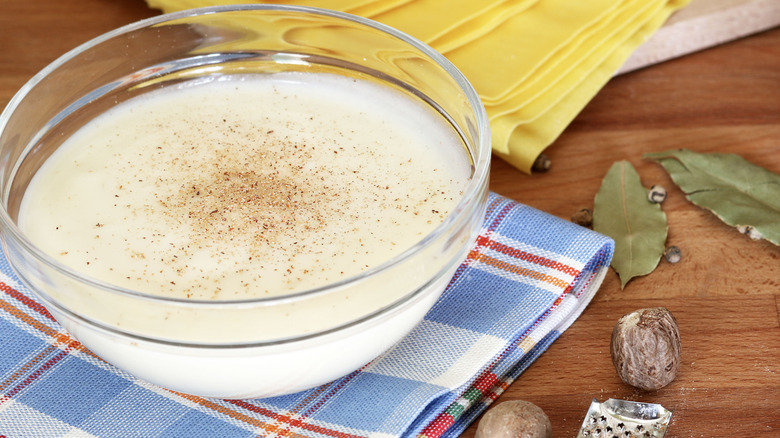 Small glass bowl of Alfredo sauce with fresh nutmeg sprinkled on top