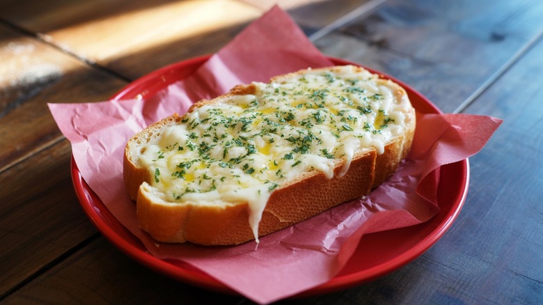 Slice of extra cheesy garlic bread on a red plate