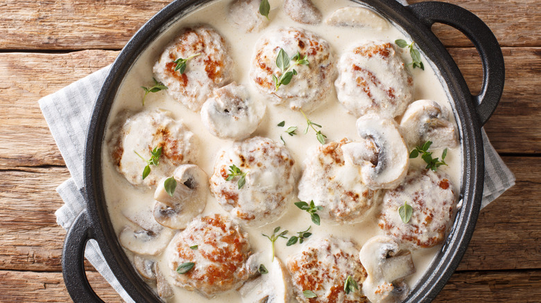 Cast iron dish full of meatballs and mushrooms in a creamy sauce
