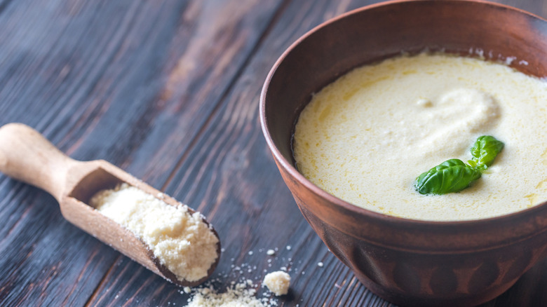Small bow of Alfredo sauce with wooden spoon full of Parmesan cheese