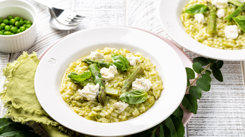 Bowl of cheesy risotto with asparagus, fresh basil, and peas