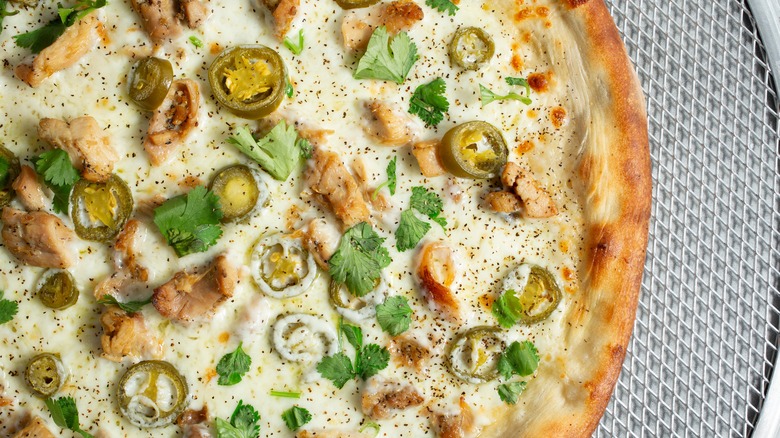 Overhead view of a creamy chicken Alfredo pizza with jalapeños