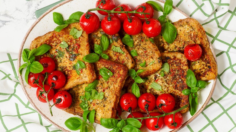 Plate of savory French toast with cherry tomatoes and fresh basil
