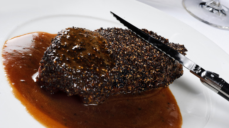 steak with crust and sauce accompanied by knife