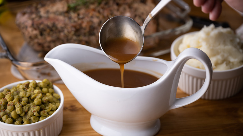 spoon pouring gravy into white boat