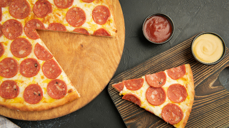 Pepperoni pizza with two cups of sauce