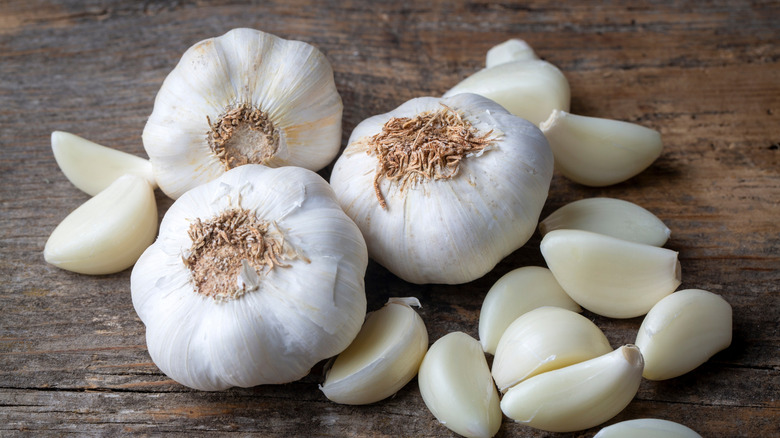 Whole garlic heads and individual cloves on wooden counter
