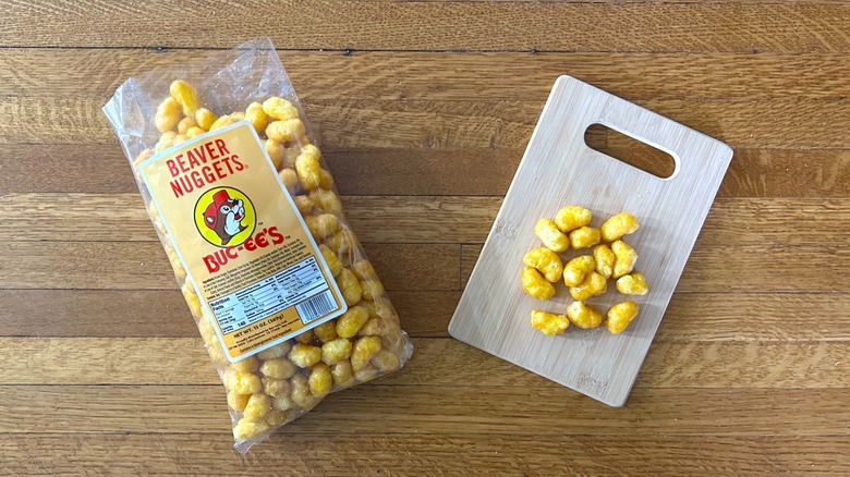 Package of and handful of Buc-ee's Beaver Nuggets on a wooden cutting board