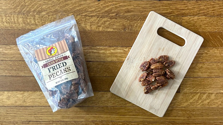 Package of and handful of Buc-ee's Cajun Style Fried Pecans on a wooden cutting board