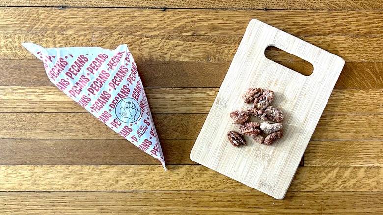 Package of and handful of Buc-ee's Glazed Pecans on a wooden cutting board