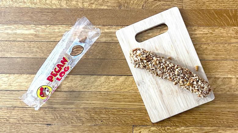 Package of and whole Buc-ee's Pecan log on a wooden cutting board