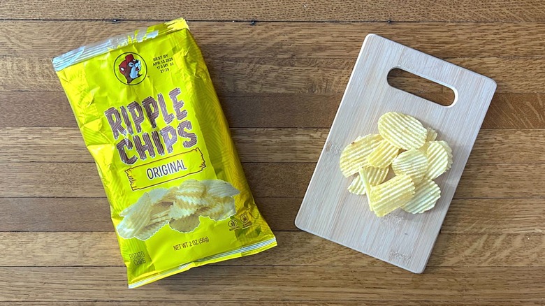 Package of and handful of Buc-ee's Ripple Chips Original on a wooden cutting board