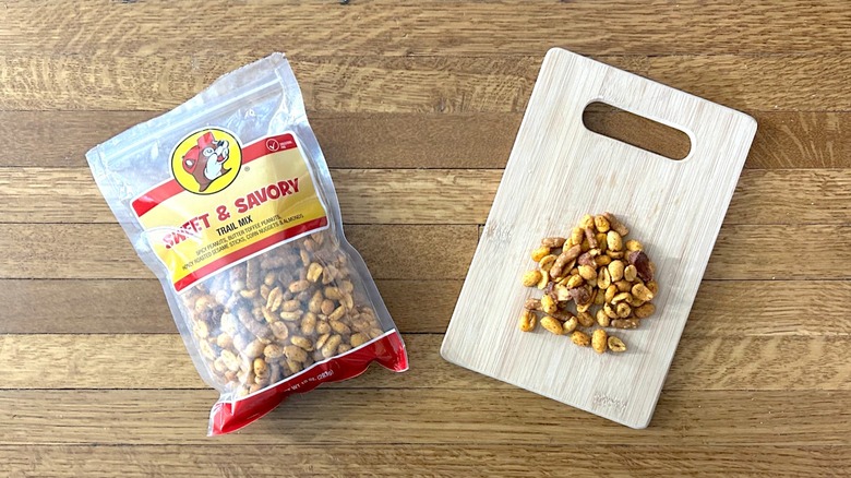Package of and handful of Buc-ee's Sweet & Savory Trail Mix on a wooden cutting board