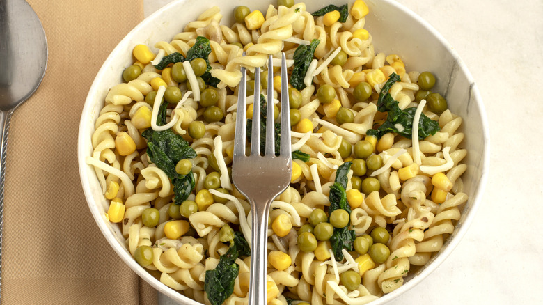 Bowl of pasta salad with peas, corn, and spinach