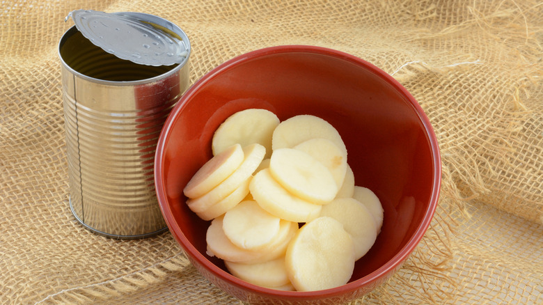 Open can alongside a bowl of sliced potatoes
