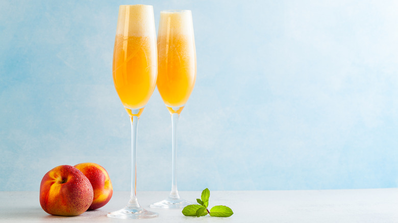 Two champagne flutes filled with peach Bellini cocktail