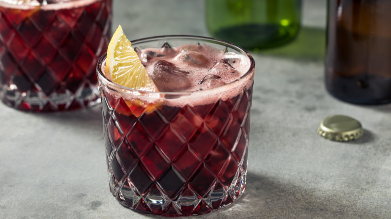Kalimotxo cocktail in rocks glass with lemon wedge garnish