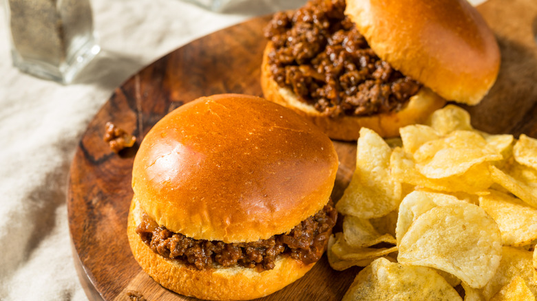 Sloppy Joe sandwiches with chips on wooden board