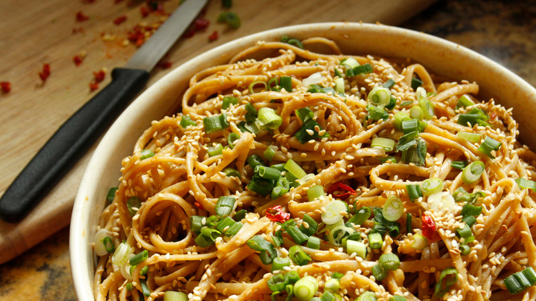A bowl of Ma Jiang Mian (cold sesame noodles) topped with sesame seeds and green onions