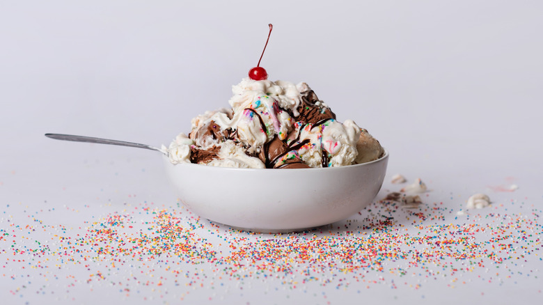 An ice cream sundae with a cherry, whipped cream, and sprinkles