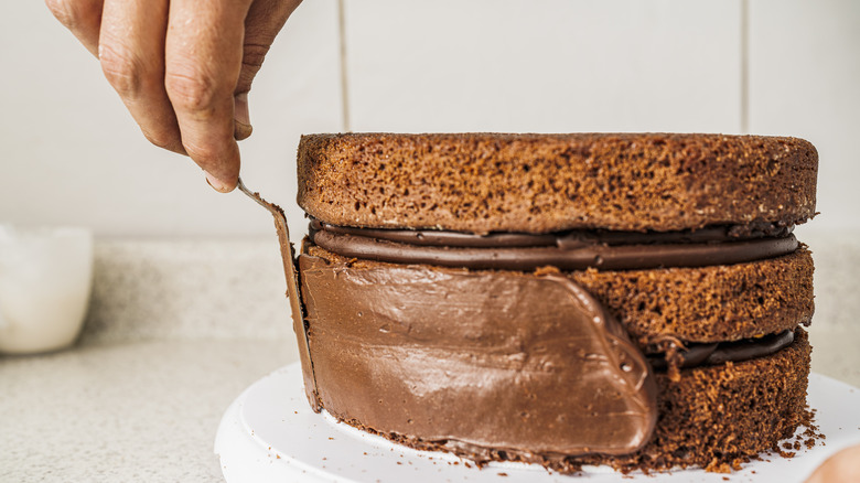 pastry chef putting frosting on chocolate cake