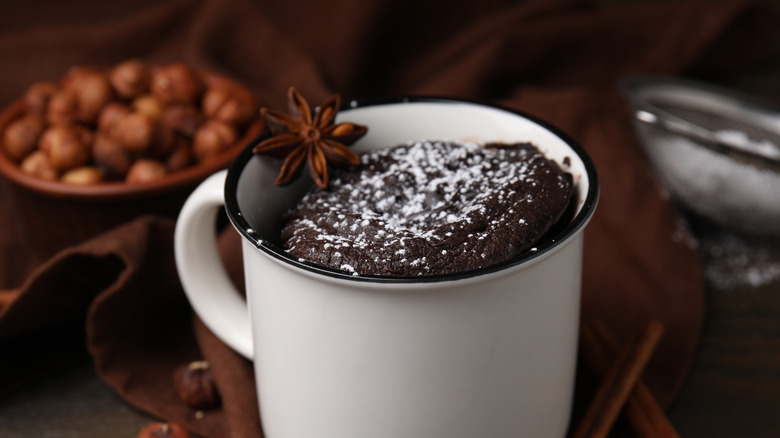A mug cake in white cup sprinkled with powdered sugar