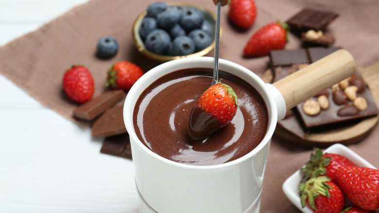 A chocolate Nutella fondue with a strawberry being dipped into it
