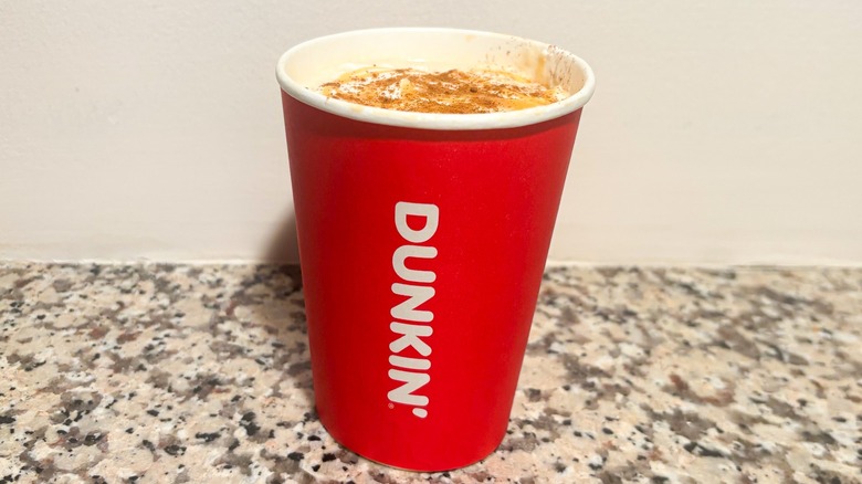 Small hot Dunkin' Pumpkin Spice Signature Latte on a granite counter top