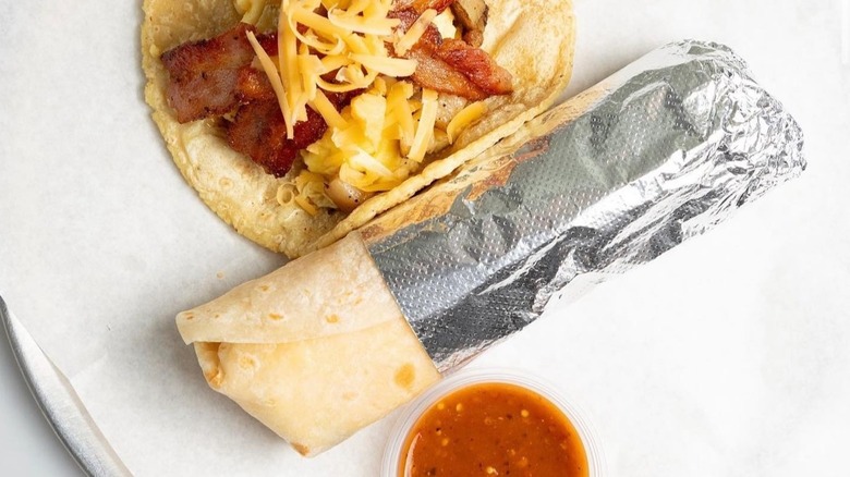 The breakfast burrito from Guisados wrapped in foil with taco and salsa