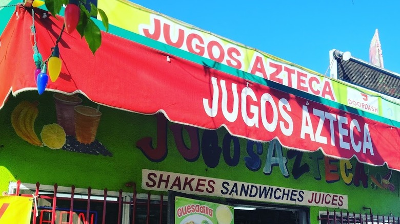 The exterior of Jugos Azteca, decorated with colorful lettering.