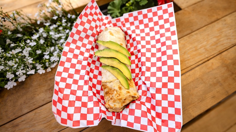 breakfast burrito with avocado in basket on table