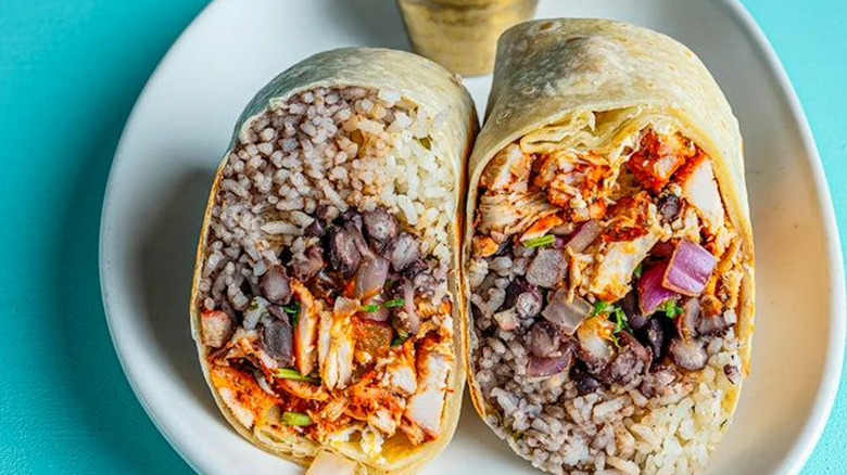 A split-open breakfast burrito on the background of a blue plate.