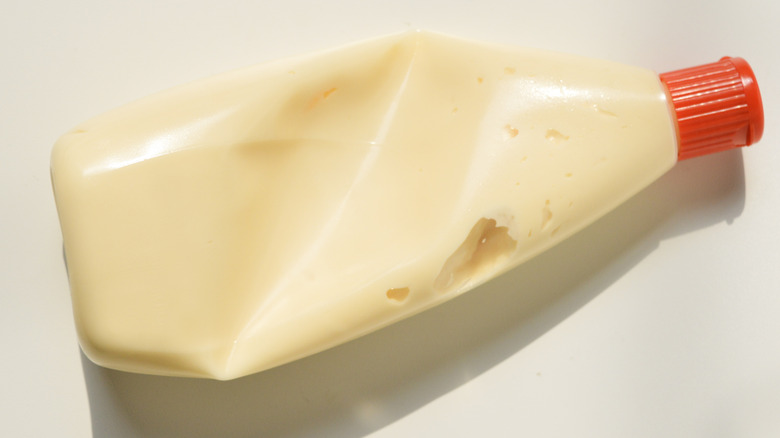 Squished mayo bottle on a white surface