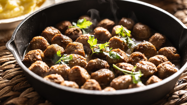 Meatballs in a cast iron skillet with herbs