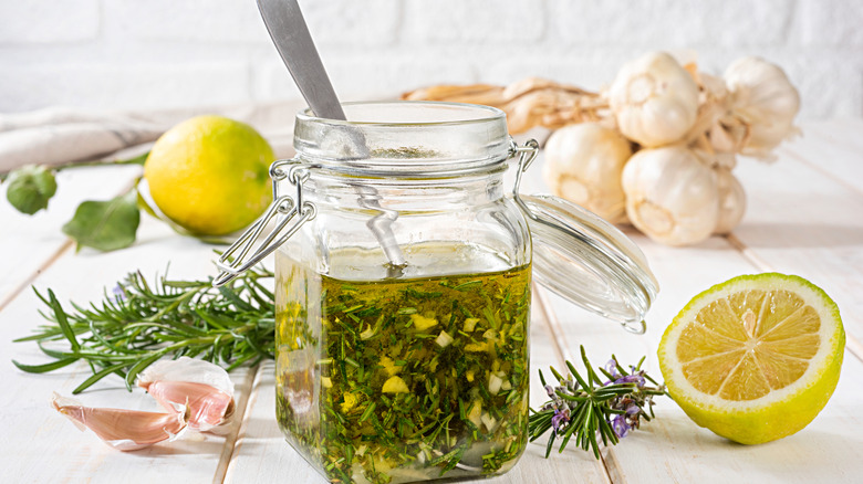 Homemade salad dressing in a jar with lemon and herbs